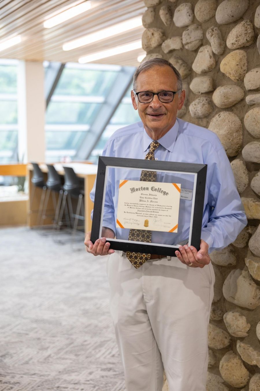 Dr. Bill Marzano, Interim Assistant Dean, stands with his Morton College diploma
